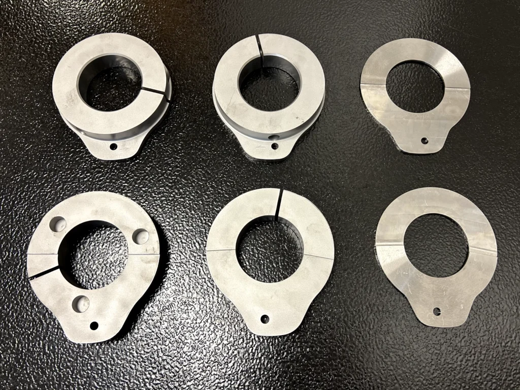 Six transfer cam plate components arranged to show multiple configurations, machined bores, split-ring sections, and mounting features.